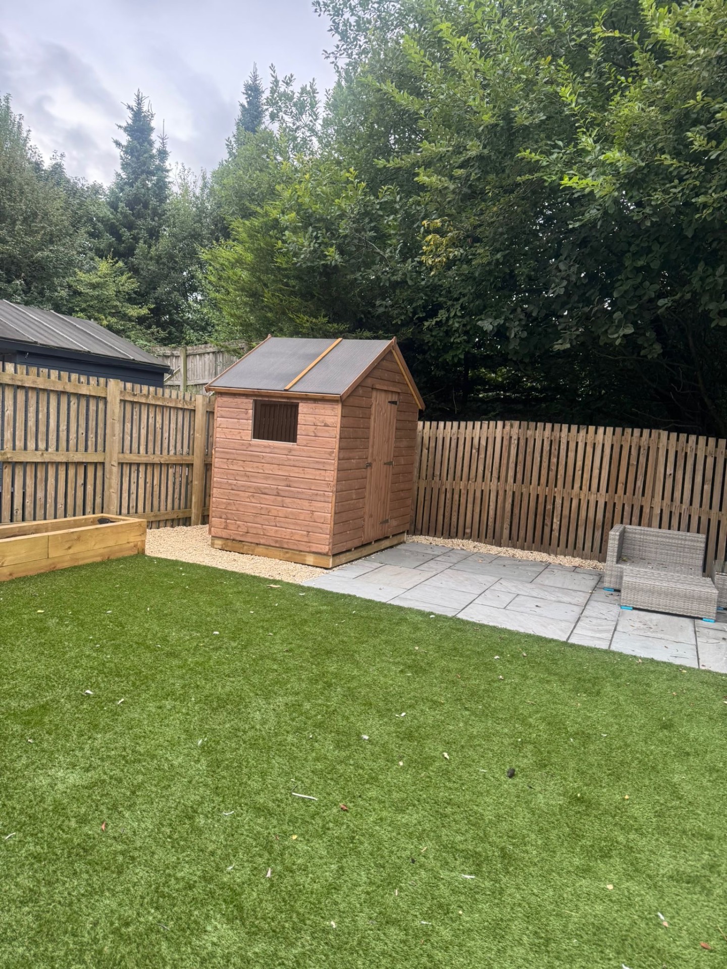 Small timber apex garden shed on gravel beside a patio