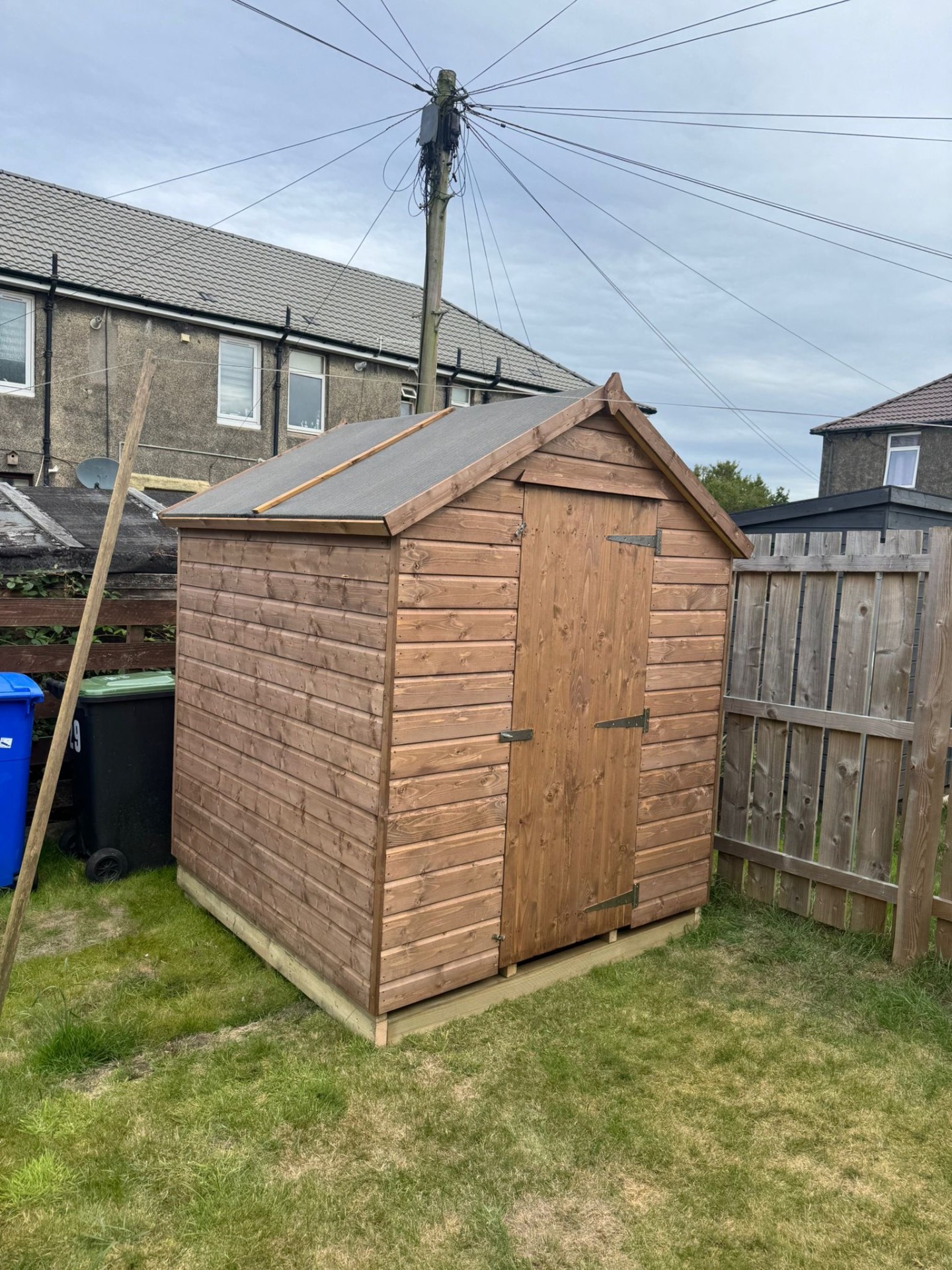 Timber apex shed with braced single door in a back garden