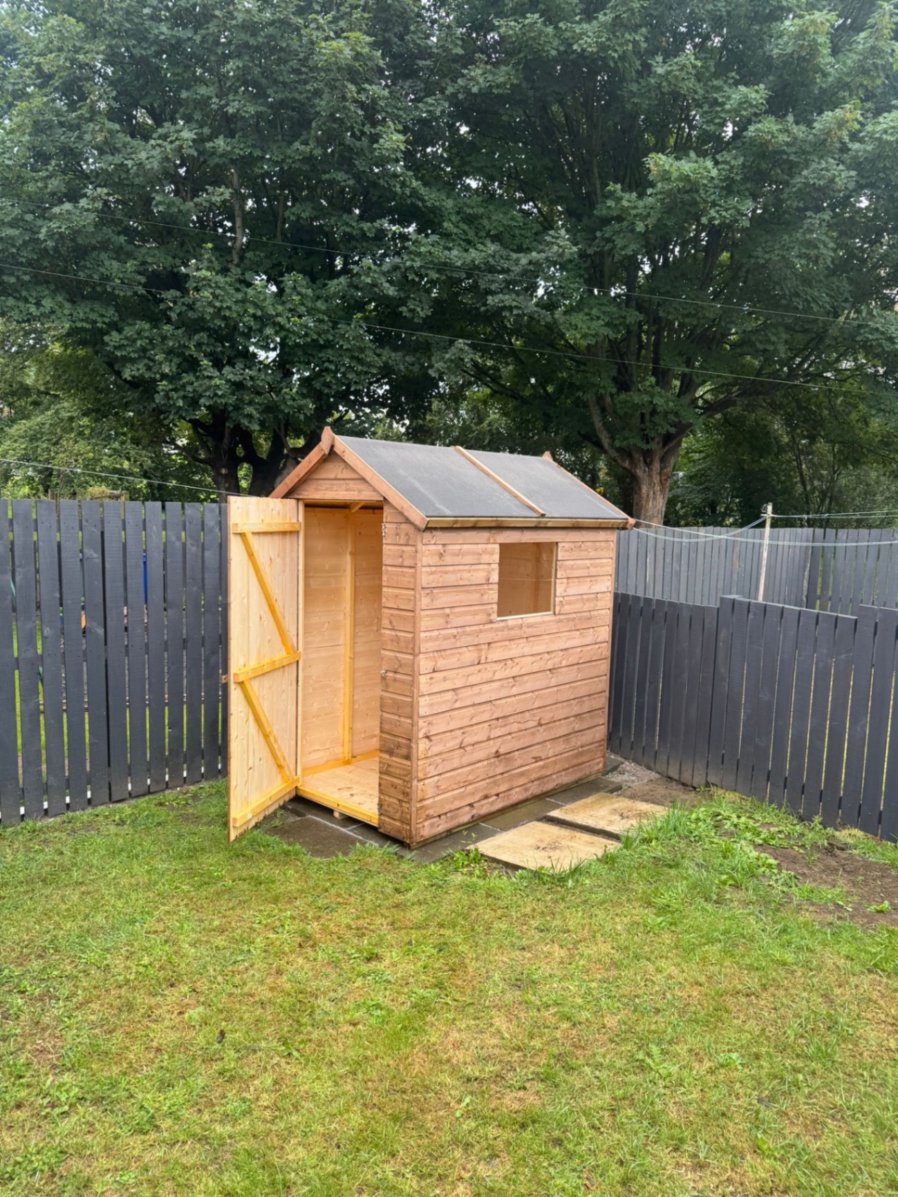 Timber apex shed with window and open door in a garden